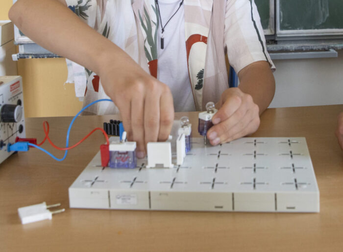 Ein Schüler bei einem Physik-Experiment zusammen mit einer Lehrerin, die ihm dabei zuschaut